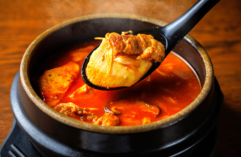 熱々の豆腐チゲ。辛みと旨みが効いた具沢山のスープ